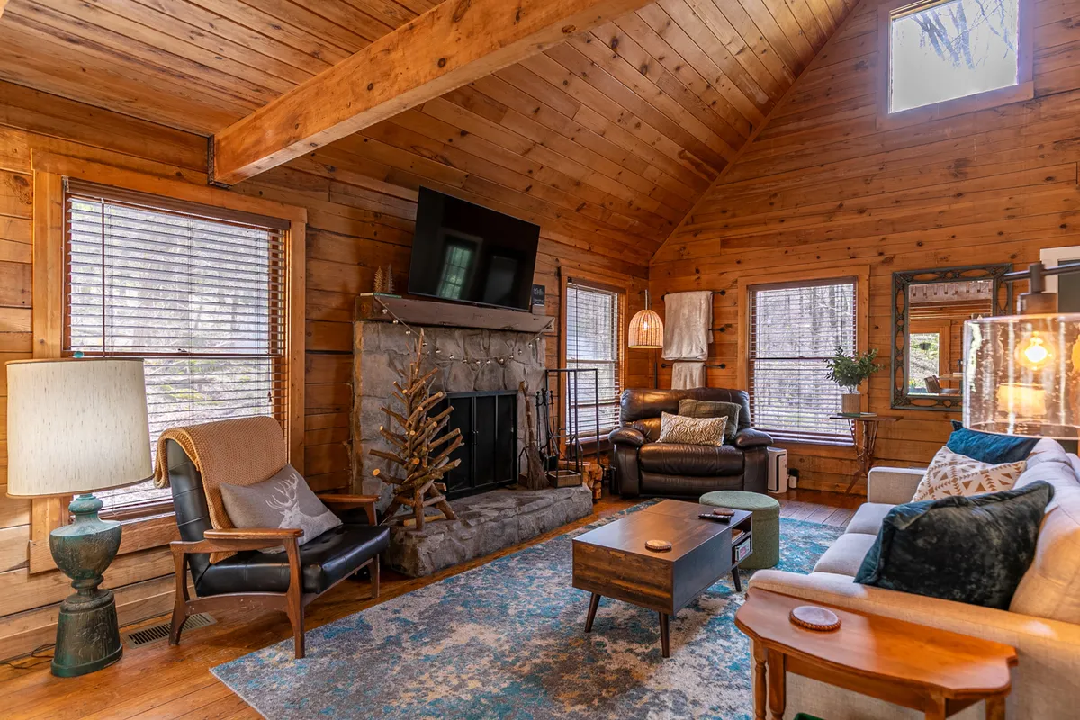 A warm, inviting living area centers around a crackling fireplace, with a plush sofa and cozy lighting creating an intimate space for relaxation. The atmosphere is perfect for snuggling up together after a day of mountain adventure or boutique shopping in nearby towns.