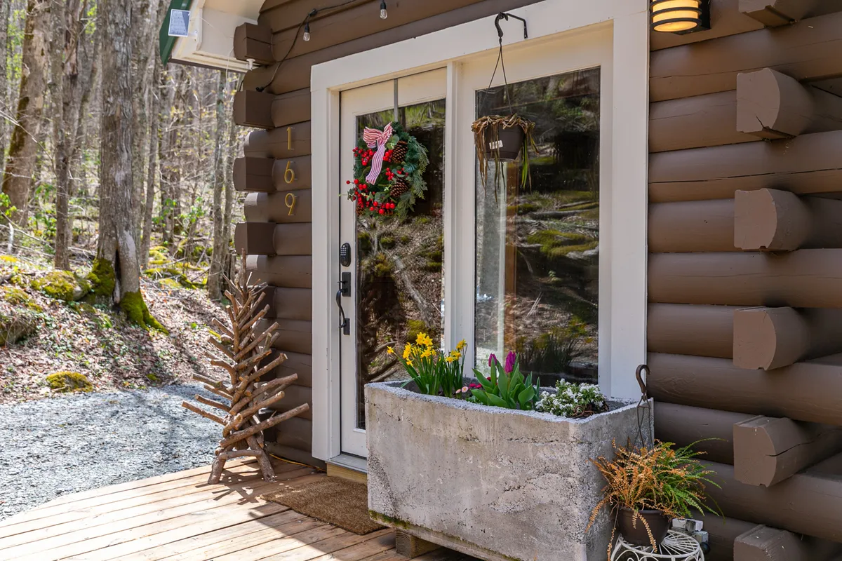 The front porch features a welcoming front door with a decorative wreath, a planter box, and a small ornamental tree. The area is neat and inviting, ideal for greeting guests and providing a sense of security.